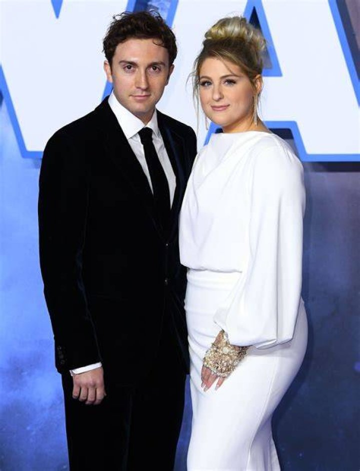Daryl Sabara and Meghan Trainor holding one of their children.